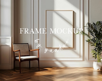 May include: A gold frame mockup with a white background. The frame is hanging on a white wall with white trim. A wooden chair with a white cushion is in the foreground. A potted plant is on the right side of the image.