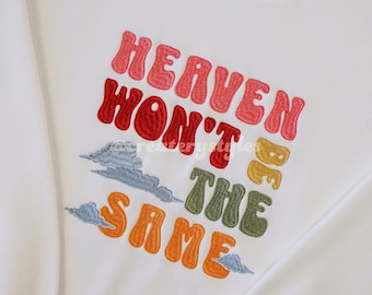 May include: White sweatshirt with a colorful embroidered design that says "Heaven won't be the same" with clouds around the text.