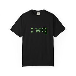 Könnte beinhalten: Schwarzes T-Shirt mit dem grünen Text ":wq" auf der Vorderseite. Das Shirt hat einen Rundhalsausschnitt und scheint aus einem weichen Material zu sein. Der Text ist in einer einfachen, serifenlosen Schriftart gehalten.