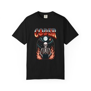 May include: Black t-shirt with a retro design featuring the word "CODER" in a gradient font. The graphic includes a skeleton working on a laptop, surrounded by flames, with a moon and planets in the background.