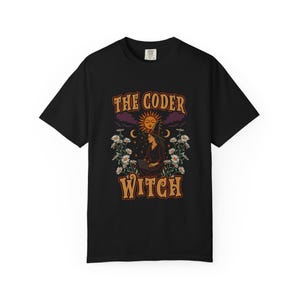 Könnte beinhalten: Schwarzes T-Shirt mit einem Grafikdesign mit dem Text "THE CODER WITCH". Das Design zeigt eine Hexe mit Laptop, Sonne und Blumen. Das Shirt hat einen Rundhalsausschnitt und kurze Ärmel.