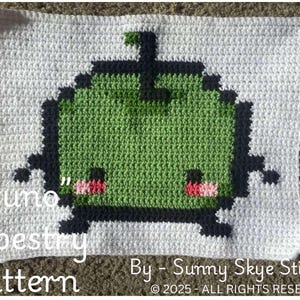May include: A crochet tapestry pattern featuring a green pixelated character with pink cheeks and the text "Juno" Tapestry Pattern By-Sunny Skye Stitches 2025-ALL RIGHTS RESERVED.