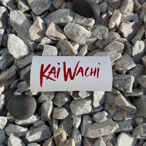 May include: A white sticker with the red text "Kai Wachi" on a background of gray gravel.