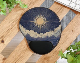 May include: Round ergonomic mouse pad featuring a celestial design with a golden sunburst against a dark blue sky, clouds, and mountains. The pad has a black wrist rest for comfort and support.