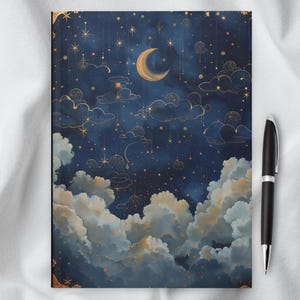 May include: A dark blue notebook cover with a gold crescent moon and stars on a background of clouds. The design is reminiscent of a night sky.