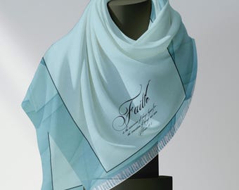 May include: A light blue scarf with a white border and a black inscription that reads "Faith is the assurance of things hoped for, the conviction of things not seen. Hebrews 11:1."