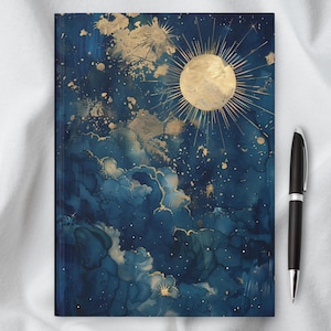 Puede incluir: Un cuaderno azul y dorado con un cielo nocturno estrellado y un diseño de sol. El cuaderno es perfecto para llevar un diario, tomar notas o hacer bocetos.