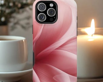 May include: A pink phone case with a floral design. The case has a glossy finish and a black camera module. The floral pattern features soft, flowing lines in shades of pink and white. The case is shown next to a lit candle and a cup.