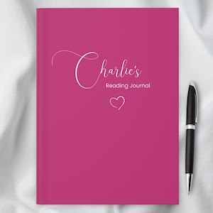 May include: A pink journal with the text "Charlie's Reading Journal" in white cursive lettering and a small white heart.