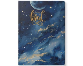 May include: A hardcover journal with a celestial design. The cover features a dark blue background with a painted night sky, a crescent moon, stars, and gold accents. The word "loved" is written in gold script.