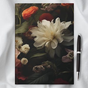 May include: A close-up of a dark floral arrangement with a white peony in the center. The flowers are surrounded by dark green leaves and other flowers in shades of pink, red, and orange.