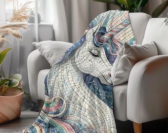 May include: A soft, mosaic-style throw blanket featuring a serene unicorn design. The blanket showcases a white unicorn head with a flowing mane and tail in shades of blue, pink, and rainbow hues. The blanket is draped over a white sofa.