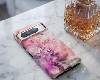 May include: A smartphone case featuring a watercolor floral design in shades of pink, purple, and peach. The case is on a white marble surface next to a crystal decanter filled with amber liquid.