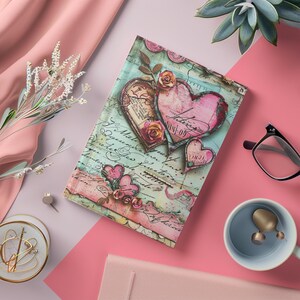 May include: A decorative journal with a vintage design featuring pink hearts, roses, and script on a teal background. The journal has a clear, glossy cover. The overall theme is romantic and vintage.