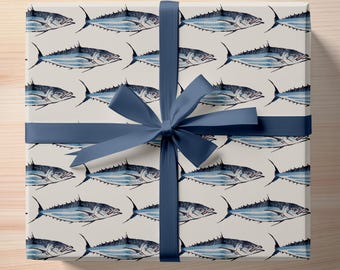 May include: A white gift box with a blue ribbon wrapped around it. The box is covered in a pattern of blue and white fish.