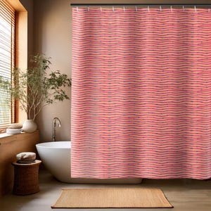 May include: A coral-colored shower curtain with a wavy pattern in shades of pink and blue. The curtain is hanging in a bathroom setting, with a white bathtub and a woven rug visible.