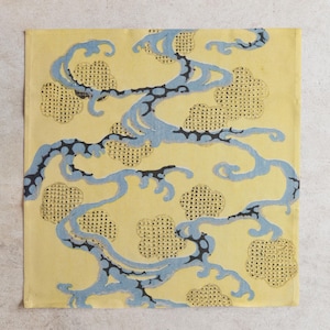 Pu&ograve; includere: Tessuto quadrato giallo con un motivo ripetuto di linee blu fluenti e forme a nuvola. Le linee sono accentuate da punti neri e le forme a nuvola hanno una trama a pois. Il design ricorda l'arte tradizionale asiatica.