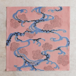 Pu&ograve; includere: Tessuto quadrato rosa con motivo ripetuto. Il design presenta linee blu fluenti con accenti neri, che ricordano l'acqua o le nuvole, e forme rosa a forma di nuvola punteggiata. L'estetica generale ricorda l'arte tradizionale asiatica.
