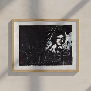 May include: A black and white print of a woman's face in a movie theater. The woman's face is the focal point of the image, and the audience is shown in silhouette in the foreground.
