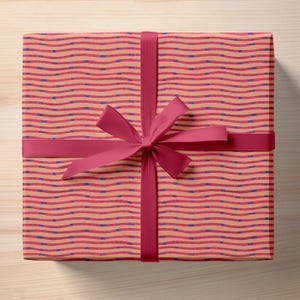 May include: A gift box wrapped in pink and orange striped paper with a red ribbon tied in a bow.