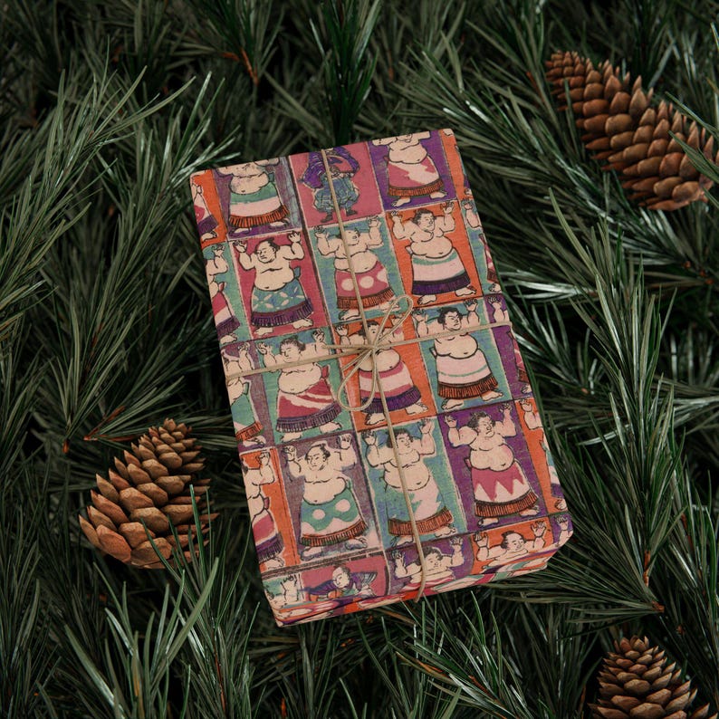 Puede incluir: Un regalo envuelto en papel de regalo colorido con un patr&oacute;n repetido de luchadores de sumo en varias poses. El papel es de color marr&oacute;n claro con un aspecto vintage.