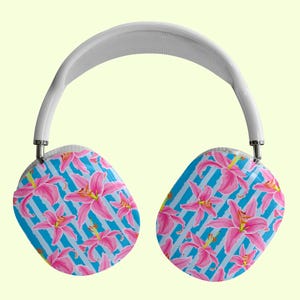 Puede incluir: Auriculares inalámbricos blancos con un patrón floral azul y rosa. Los auriculares tienen una diadema blanca y almohadillas para los oídos con un diseño floral.