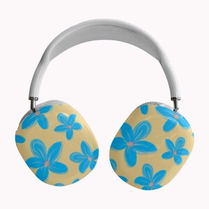 May include: White over-ear headphones with a cream-colored headband and earcups. The earcups feature a light tan background with a pattern of blue flowers with pink centers. The headphones have silver metal accents.