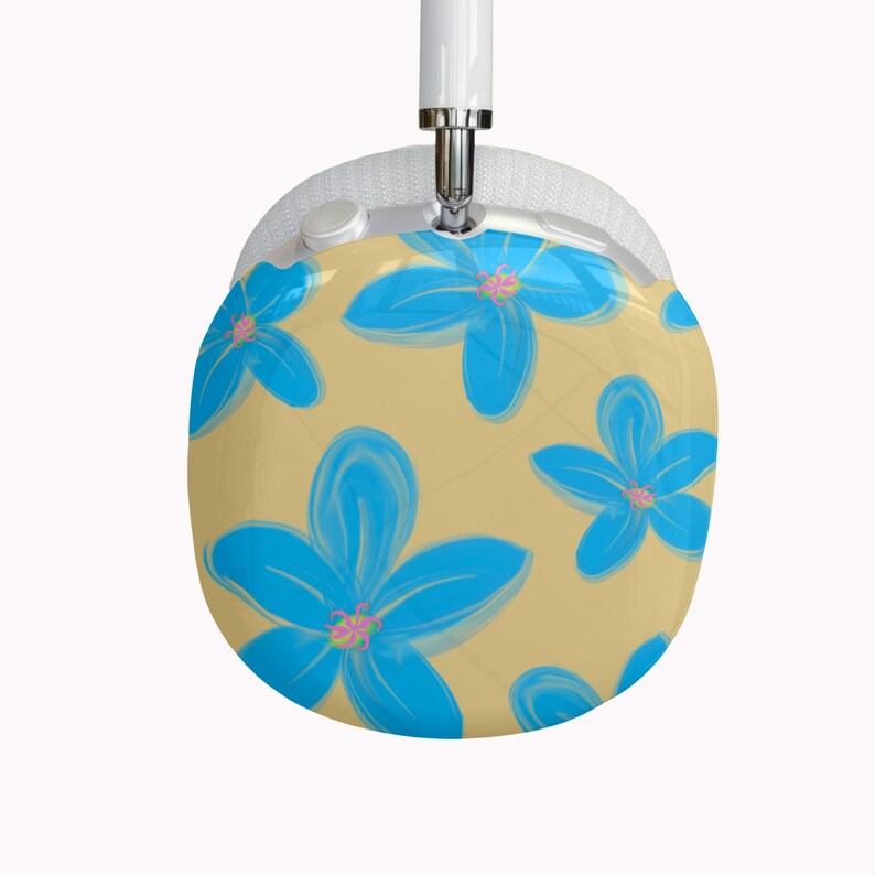 May include: Over-ear headphones with a floral design. The earcups feature a pattern of large, stylized blue flowers with pink centers on a tan background. The headband and earcups are white.