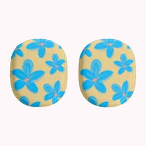 May include: Two oval-shaped earrings with a light yellow background and a repeating pattern of blue flowers with pink centers. The earrings are a fun and colorful accessory.