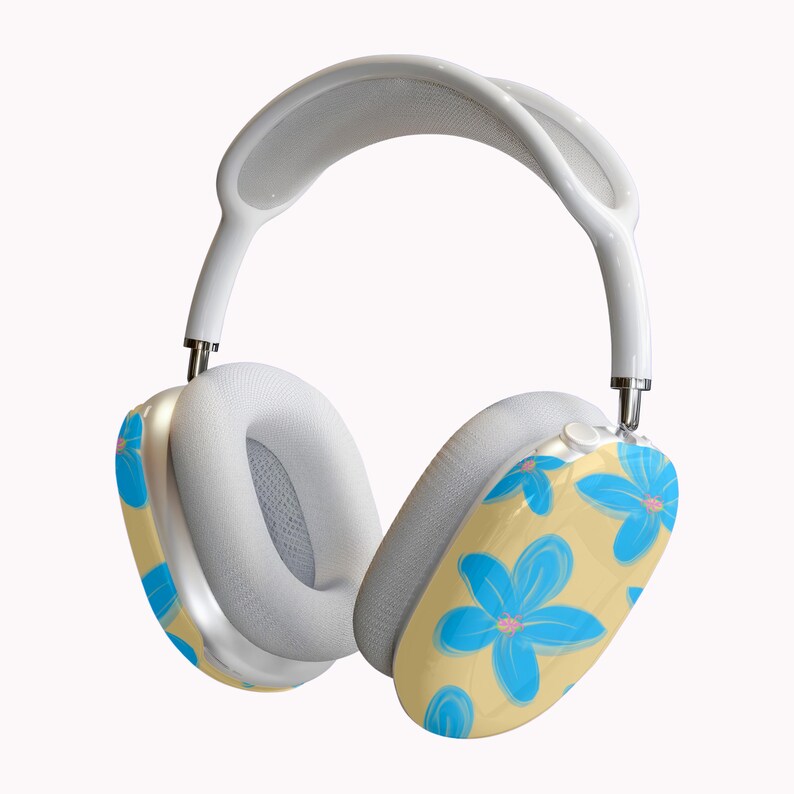 May include: White over-ear headphones with a floral design. The earcups have a light yellow background with blue flowers and pink centers. The headband and ear cushions are white.