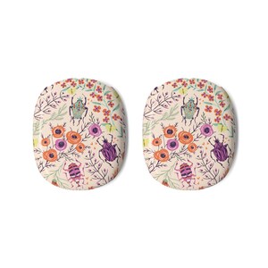 May include: Two oval-shaped decorative items with a floral and insect pattern. The design features colorful flowers, green leaves, and various beetles on a cream background. The color palette includes orange, purple, and pink.