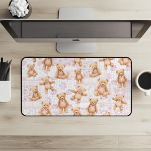 Könnte beinhalten: Eine rechteckige Schreibtischunterlage mit einem sich wiederholenden Muster aus hellbraunen Teddybären mit kleinen rosa Schleifen um den Hals, vor einem Hintergrund aus zartrosa und weißen Karos sowie feinen Blumenmotiven in Rosa- und Grüntönen.