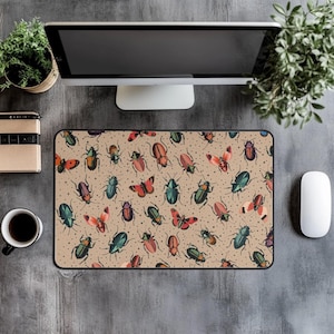May include: Beige rectangular mousepad featuring a pattern of colorful beetles and butterflies. The insects are in shades of red, green, orange, and blue, with a scattering of small white stars. The mousepad has a black border.