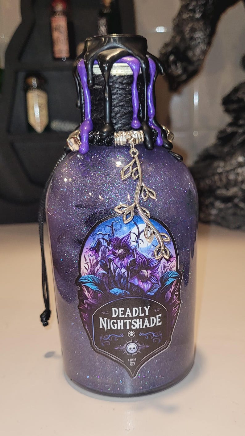 May include: A purple glass bottle with a black wax seal and a silver charm. The bottle is filled with glitter and has a label that reads "Deadly Nightshade".