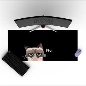 May include: Black desk mat with a grumpy cat illustration and the word "No." A black keyboard and a purple mouse are visible. A curved computer monitor is in the background. The mat is rectangular.