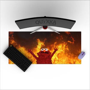 May include: A red, furry monster with large eyes is surrounded by flames. The monster is standing with its arms raised in the air. The background is a fiery orange and yellow.