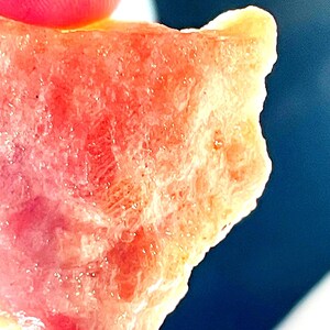 May include: A close-up of a pink and orange crystal with a rough, textured surface.