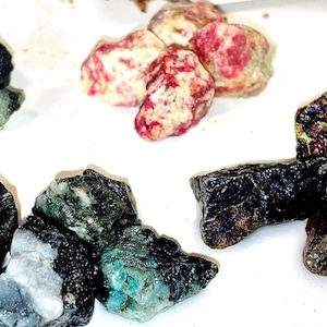 Ensemble de minéraux bruts : émeraude, tsavorite chromifère, matrice de spinelle et chalcopyrite.