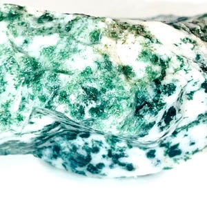 May include: A rough, green and white agate stone with a swirling pattern. The stone has a natural, unpolished finish.