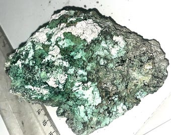 May include: A rough, irregularly shaped rock with a green and white mineral deposit. The rock has a mottled appearance with patches of green and white.