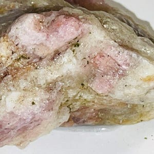 Peut inclure: Un cristal brut, blanc et rose, avec une apparence translucide. Le cristal a un aspect naturel et non poli.