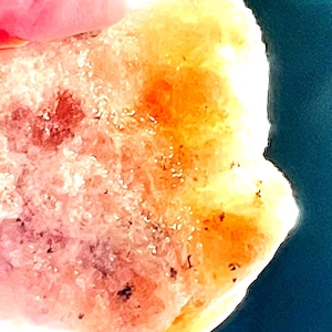 Puede incluir: Primer plano de un cristal rosa y naranja con una superficie rugosa y texturizada.