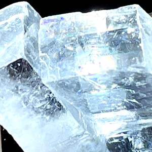 May include: A large, clear, crystalline mineral with a slightly blue hue. The crystal has a unique, geometric shape with many facets.