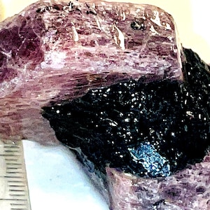 以下が含まれることがあります： 層状の縞模様のテクスチャを持つ、大きく、粗い、紫と黒の結晶。結晶は、ほぼ黒に近い暗い中心と、紫色の外層を持っています。
