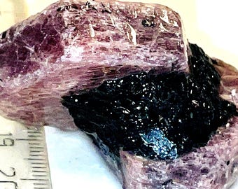 May include: A large, rough, purple and black crystal with a layered, striated texture. The crystal has a dark, almost black, center with a purple outer layer.