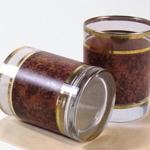 May include: Two clear glass tumblers featuring a dark brown mottled texture band around the centre. Each glass is accented with thin gold horizontal stripes at the top and bottom of the textured section, with clear glass at the base and rim.