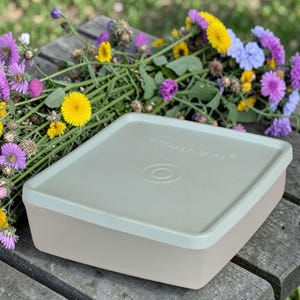 Op de afbeelding: Een witte keramische mok met een zwarte handgreep en de tekst "But First, Coffee" in een vetgedrukte, zwarte letter. De mok staat op een wit oppervlak, wat het strakke ontwerp benadrukt.