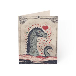 May include: Greeting card featuring a sea serpent with a heart-shaped balloon and a spray of hearts. The illustration is in shades of gray, red, and beige, with a vintage aesthetic. The card is folded and has a blank interior.