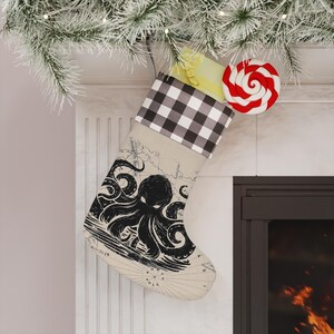 May include: A Christmas stocking featuring a black and white buffalo plaid cuff and a beige body printed with a vintage-style map background and a large black octopus illustration. The stocking is hanging from a fireplace mantel.