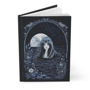 May include: A hardcover book with a black cover featuring a graphic illustration of a person wearing a seal pelt hood in water. The scene includes a full moon, floral borders, and two seals at the top, all rendered in shades of blue and white.